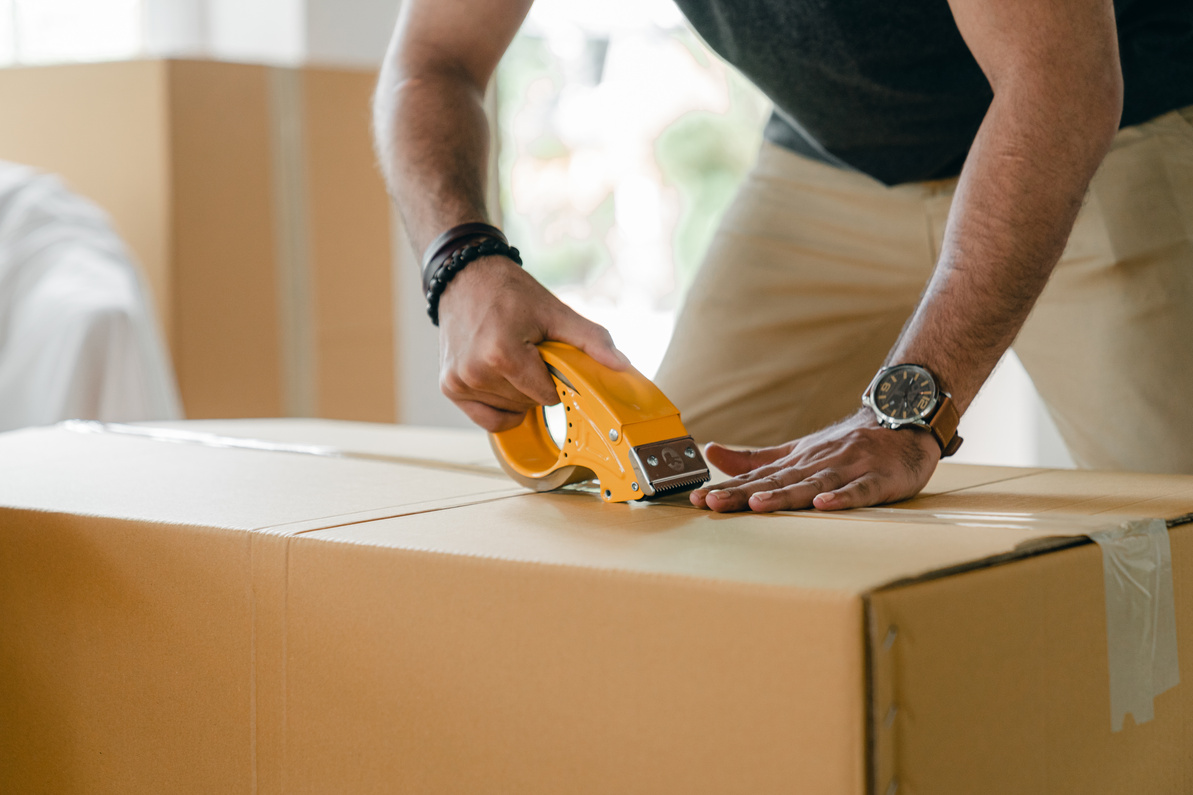 Crop faceless man preparing box for shipping